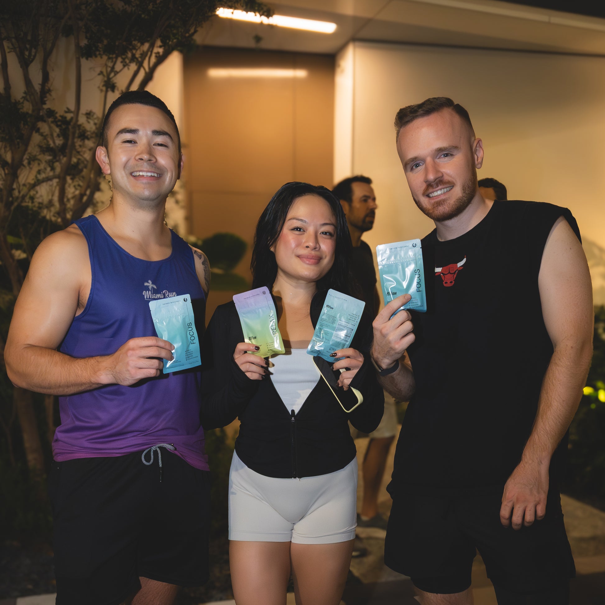 Three people standing together, holding Hiflow gum pouches.