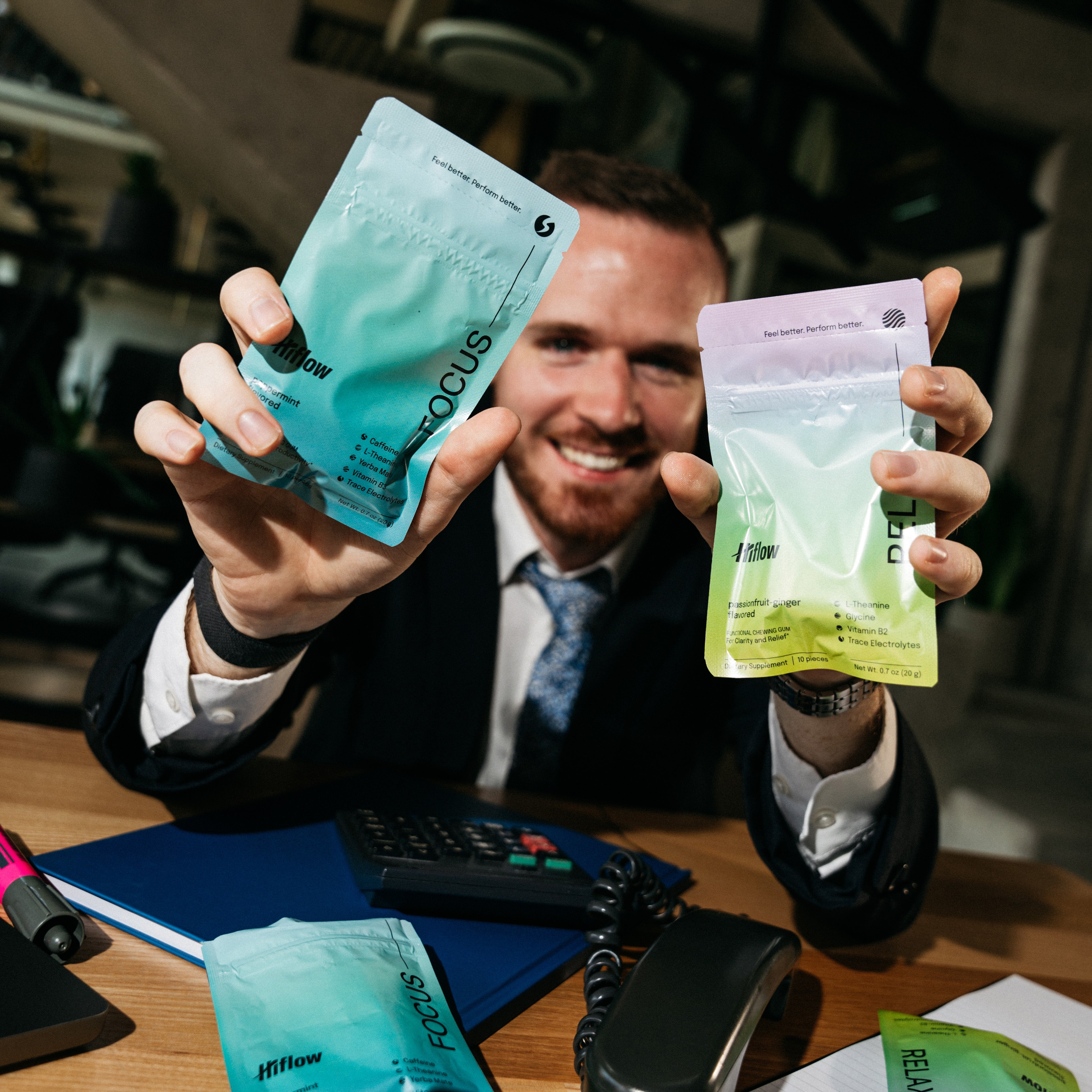 A smiling man holding two gum pouches, a Hiflow Focus and a Hiflow Relax.