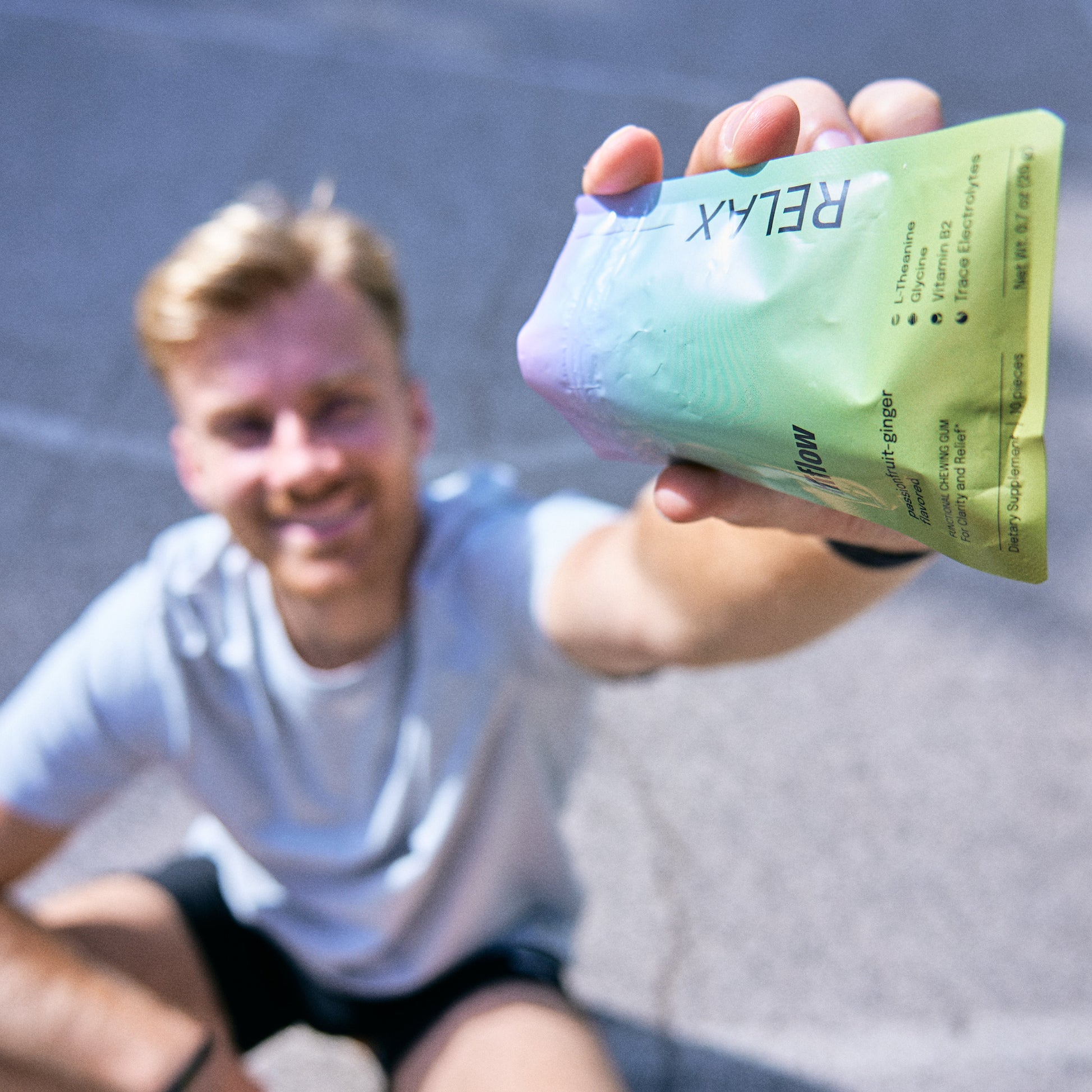 Smiling athlete holding a Hiflow Relax gum pouch outdoors.