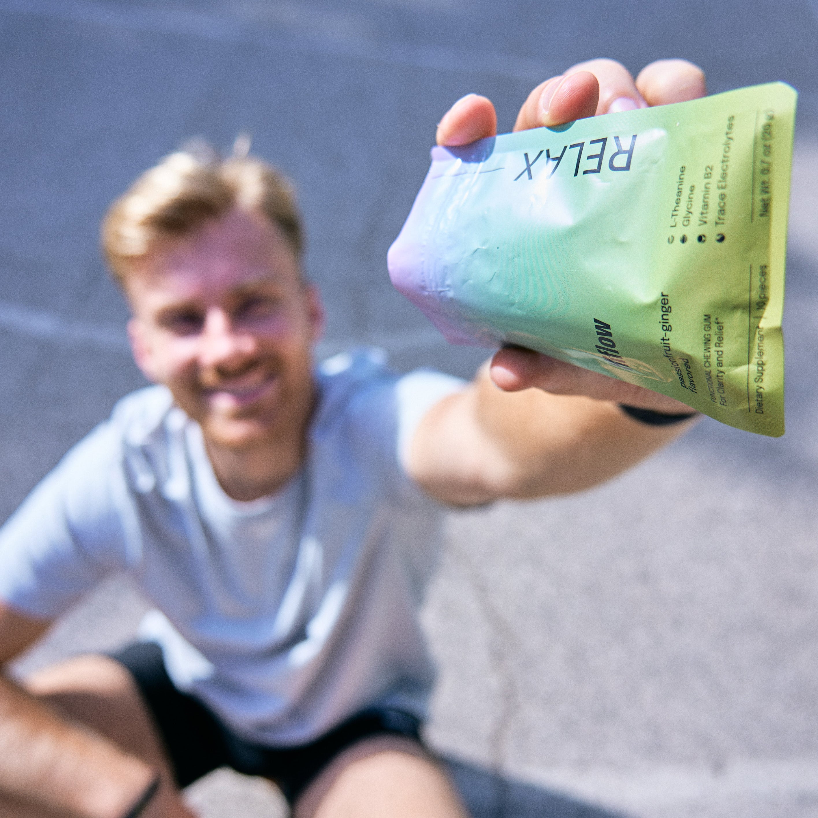 Smiling athlete holding a Hiflow Relax gum pouch outdoors.