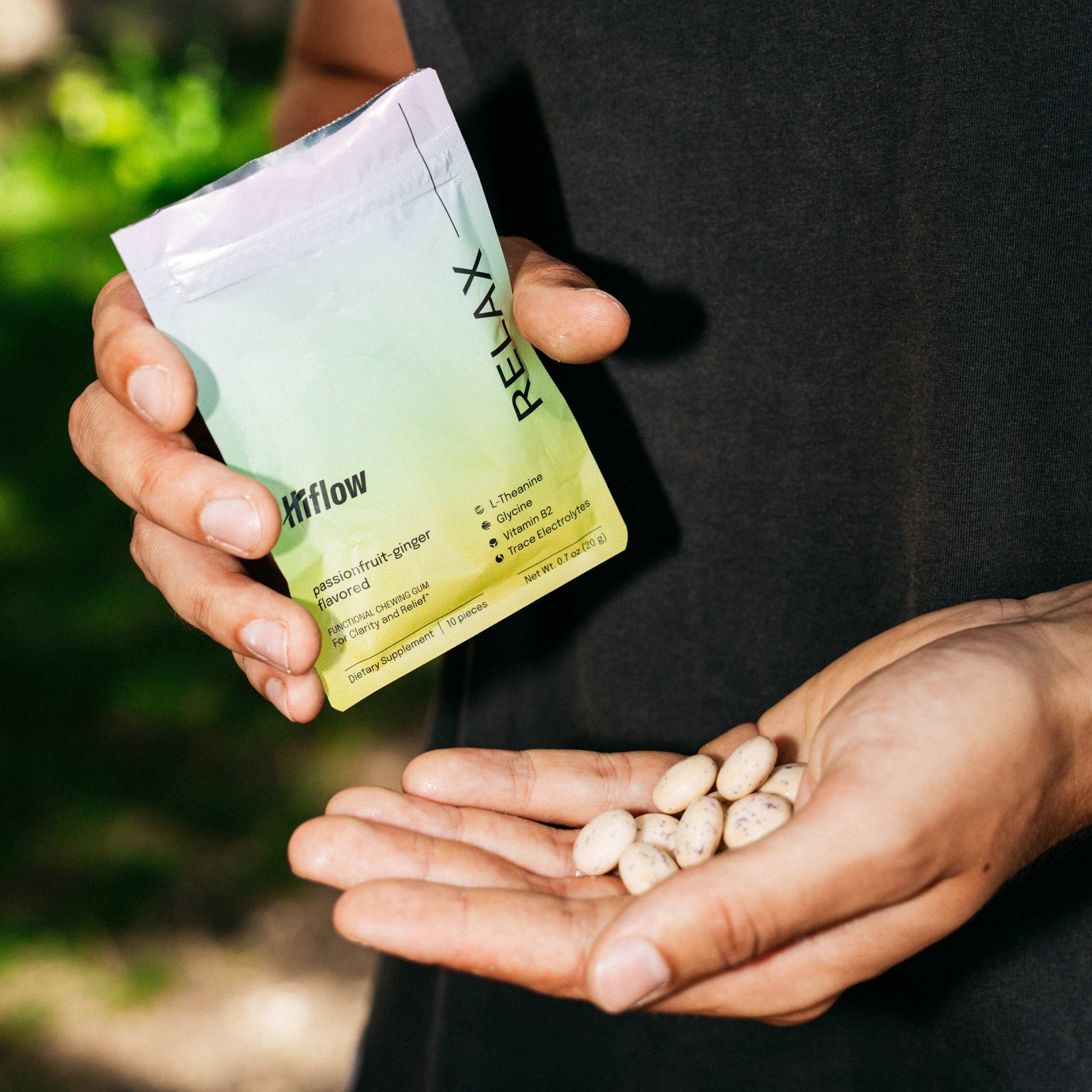 Person holding a 'HiFlow Relax' pouch with gum pieces in their palm against a blurred natural background
