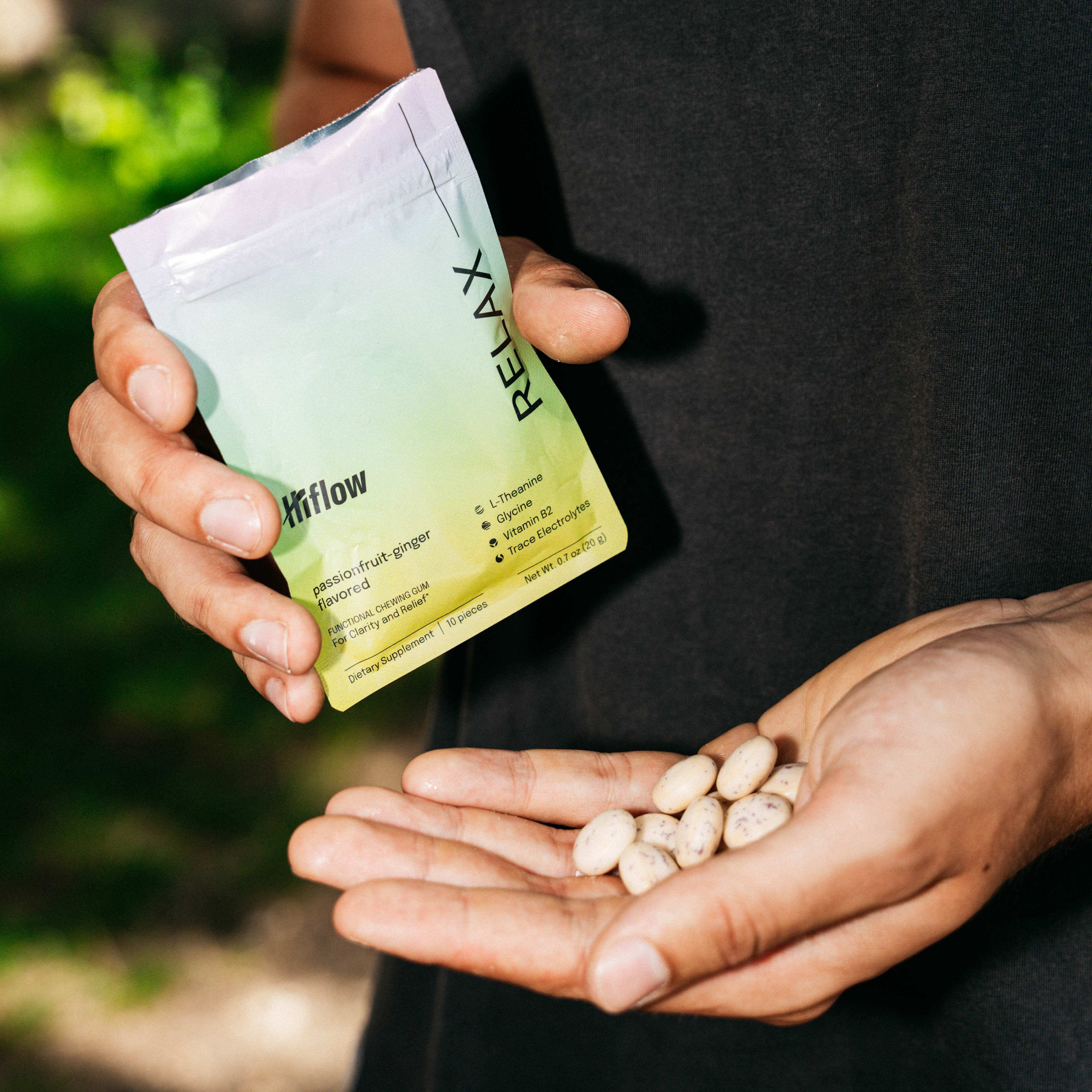 Person holding a 'HiFlow Relax' pouch with gum pieces in their palm against a blurred natural background